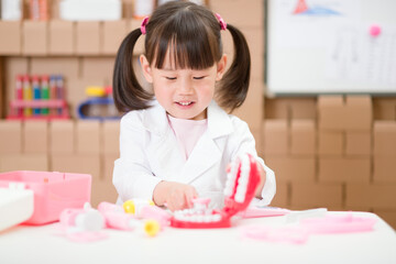 young  girl pretend play dentist role at home