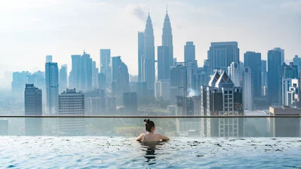 Outdoor kussens Asian travel concept. young woman enjoying with the city sky view from hotel roof top swimming pool, beautiful girl lifestyle outdoor in vacation time © chokniti
