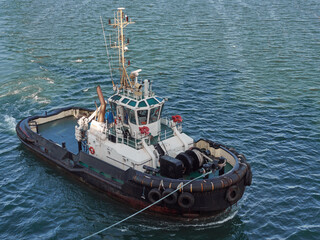 Tug boat approaching to the container vessel for mooring near the port.
