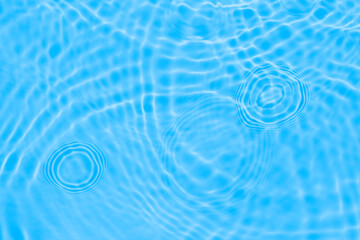 Surface of light deep blue transparent swimming pool water texture with circles on the water. Trendy abstract nature background. Water waves in sun light reflections