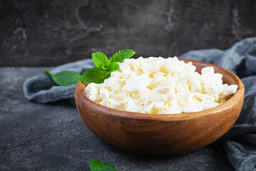 Bowl of cottage cheese on dark background. Fresh homemade cottage cheese