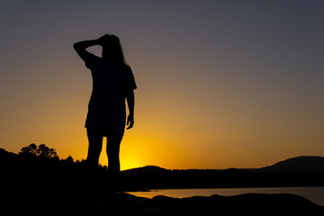 Silhouette of woman at sunset watching the horizon. Overcoming life's difficulties. Concept of reflection and thought. Selective focus. Copy space. Self-confidence.