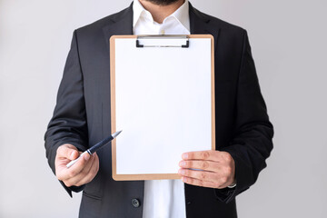Business man in suit holding a blank clipboard