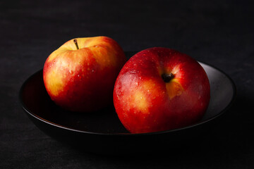 red apples in a black plate on a black background dark photo