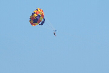 This person is parasailing high in the sky above the ocean and beach in Ocean City, NJ.