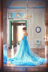 Beautiful young girl in a blue ball gown in the the historical palace interiors