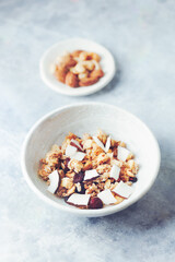 Bowl of granola with nuts, cranberry and cocoanut. Concept for a tasty and healthy meal. Stone background. Close up. 