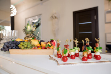 Canapes with cheese, shrimps and cherry tomatoes on skewers. Blurred background. Fruit on a blurred background.