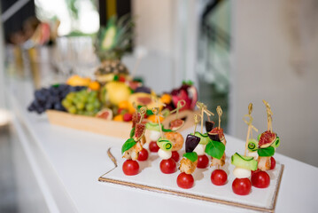 Canapes with cheese, shrimps and cherry tomatoes on skewers. Blurred background. Fruit on a blurred background.