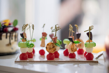 Canapes with cheese, shrimps and cherry tomatoes on skewers. Blurred background
