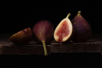 Photo of figs on a wooden board with a black background.