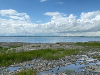 Clouds over the riverfront. Seashore at low tide.