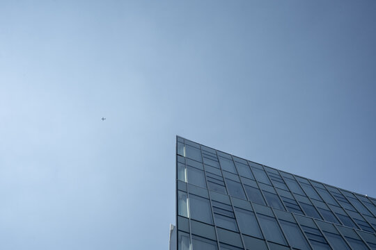 Small Airplane flying over a modern building