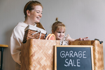 A young woman and her daughter packed up for a garage sale and donation. Box with the words 