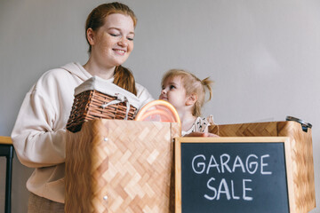 A young woman and her daughter packed up for a garage sale and donation. Box with the words 