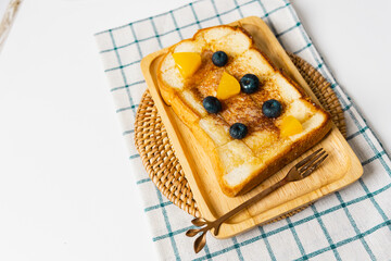 french toast with honey syrup and blueberry topping  on wooden plate