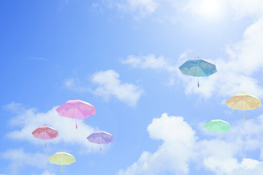 カラフルな空に浮かぶビニール傘の青空背景画像/晴れ/日差し/雨/アンブレラ