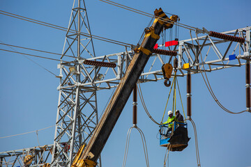 Male workers Installation of high-voltage transmission electricity poles on the crane