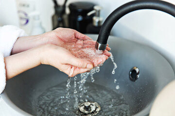 The girl washes and her hands with water in the washbowl