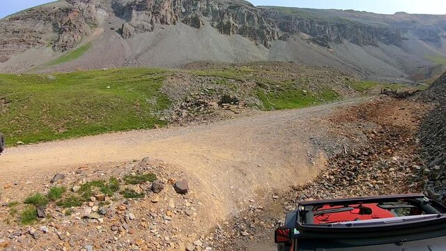 Following another 4WD vehicle making a hairpin curve on Black Bear Pass trail above Ingram Basin near Telluride CO; spectacular mountain views; concept of adventure, exploration and adrenaline rush