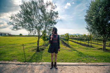 Trendy boho chic style back of woman opening arms for freedom feeling in front of a beautiful vineyard landscape - concept of outdoor and travel people lifestyle - 