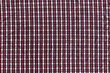 The texture of natural cotton fabric in a small cage is burgundy, white and brown. Abstract background of natural fabric. Coarse plain fabric.