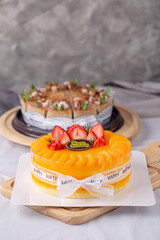 Fresh orange cake soft fudge decorated with orange pulp and strawberry for birthday cake on wooden board.