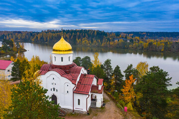 Karelia, Russia. Orthodox Church on the river Bank. View of the temple from a height. Church on the background of autumn trees. Religious building. Autumn landscape with a temple.