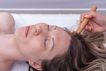 Massage the roots of the girl's hair using the wooden roller massager, close-up. Massage hair roots...