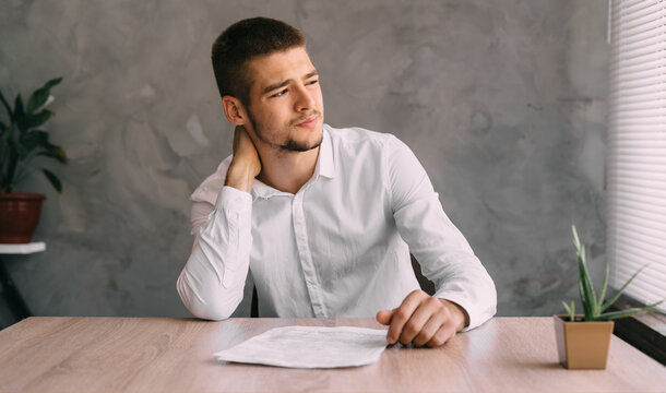 pinched cervical vertebrae of a young office worker. Fibromyalgia of a man with sedentary work. Poor lifestyle and posture. The guy is holding a sore neck. Massage of the cervical spine.