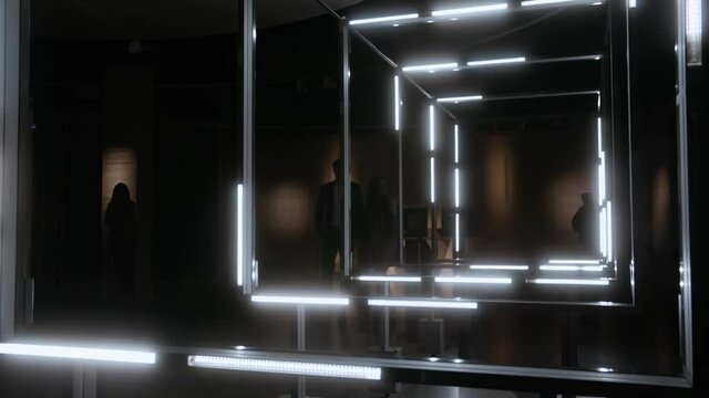 Futuristic art installation of led squares blinking lights and people walking in the back on a date