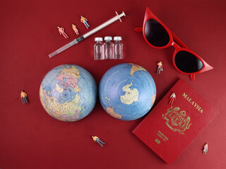 Vaccine passport Malaysia red sunglass world atlas globe map north south pole on red paper background world travel tour vacation mini human figures medical needle syringe bottle