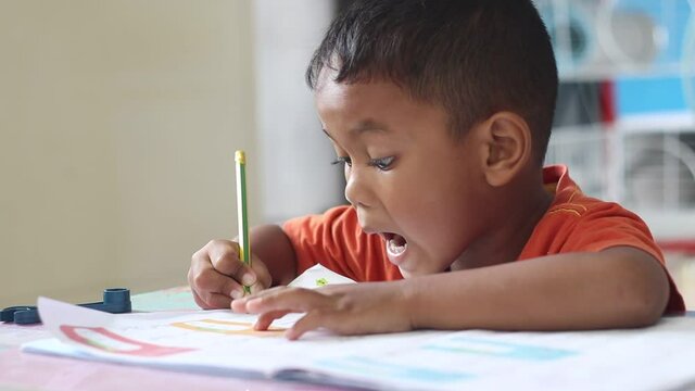 Cute child boy studying and thinking at the home. Cute child boy artist playing alone drawing coloring picture with pencils, focused smart preschool child enjoying creative art hob.