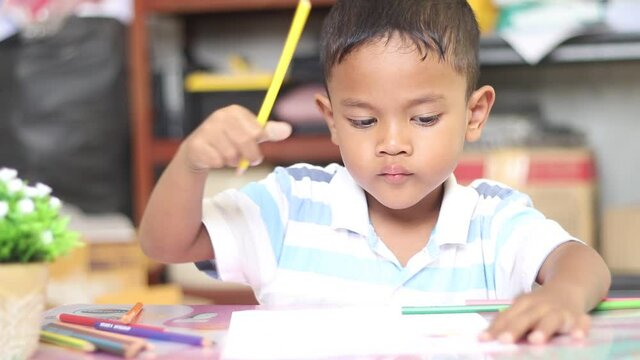 Cute child boy studying and thinking at the home. Cute child boy artist playing alone drawing coloring picture with pencils, focused smart preschool child enjoying creative art hob.