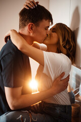 Side view of young couple kissing and hugging on kitchen