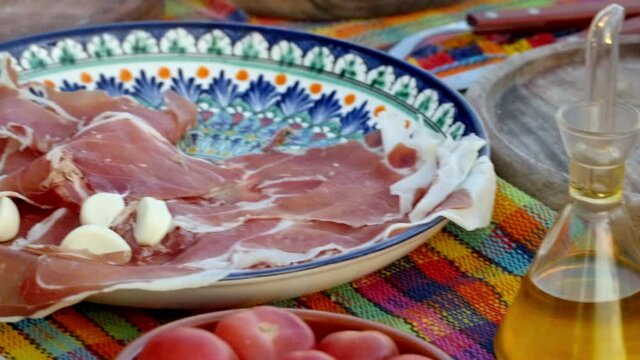 image of a hand cooking a plate of bread with tomato garlic oil salt and ham called bread with tomato and ham in a detail plane where you can see all the colors of the food. bodegon