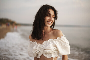 Portrait of young brunette haired woman at the beach at sunset