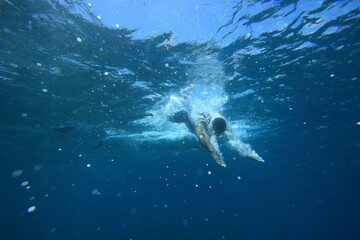 Fototapeta na wymiar underwater photo of man diving into the refreshing clear blue ocean