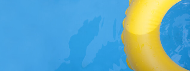 Detail of yellow inflatable ring floating in swimming pool in sunny day. Full frame, top view.