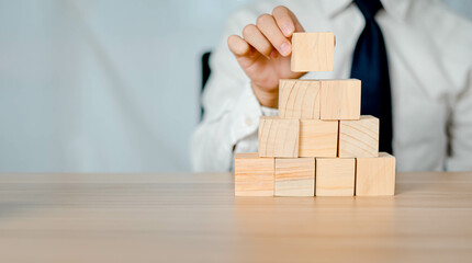 Businessman arranging stack of a wooden cube as an empty staircase. Business planning and investment ideas, find achievements, goals in life, with copy space.