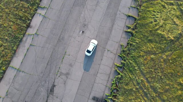 Aerial shot of white car riding through empty road. 