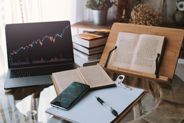 Stock market analysis on smartphone and laptop featuring stock tickers or graphs, Learn trade stock market and the cryptocurrency market at home,Young money concept.