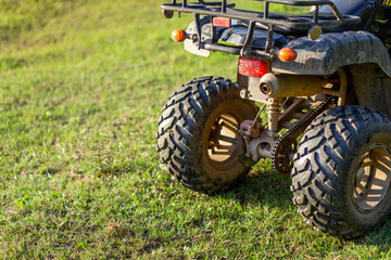selective focus ATV tires, ATV rear wheels parked on a light green lawn Evening gives light and soft feeling. There is space for the left text.