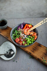 Bowl with rice, shrimp, salted salmon, edamame beans, red cabbage and fresh cucumbers. Healthy food in Asian style.