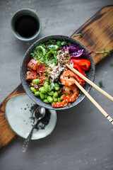 Bowl with rice, shrimp, salted salmon, edamame beans, red cabbage and fresh cucumbers. Healthy food in Asian style.