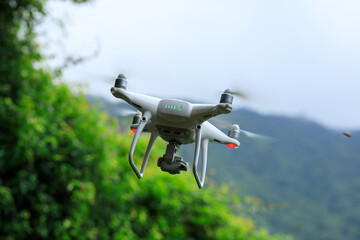 White drone with camera flying in summer mountains