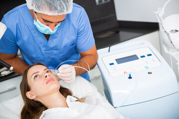 Young woman receiving innovative anti-aging carboxytherapy procedure for face skin in aesthetic medicine office, infusing of carbon dioxide under skin for collagen boosting