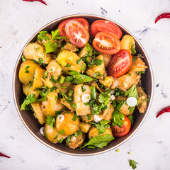 Classic potato salad onions and parsley with chopped tomatoes in a plate, top view