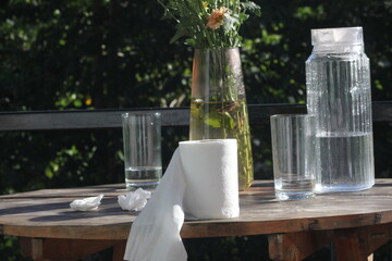 A glass of water and used tissues and a pitcher of water are placed on the table.