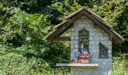 Fototapeta na wymiar popular devotion, floral tributes to a chapel in the woods dedicated to the Virgin Mary. Piedmont, Italy.